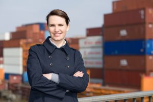 Portrait of satisfied business woman in front of cargo container terminal