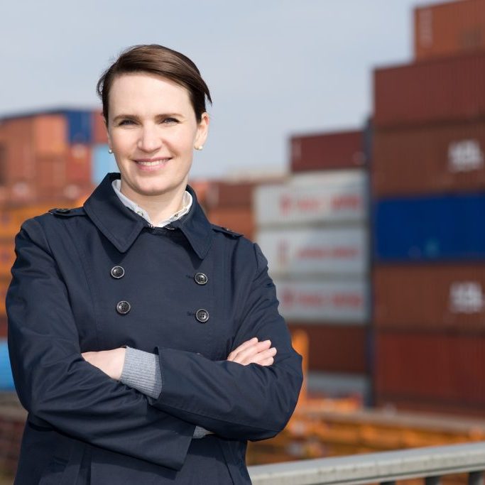 Portrait of satisfied business woman in front of cargo container terminal